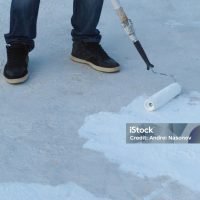 Man applies waterproof and thermal insulation of a roof from rain and sun.